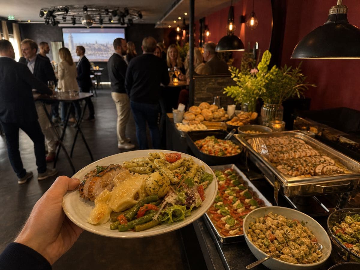 Handyfoto von einem Teller mit Catering und Gästen im Hintergrund